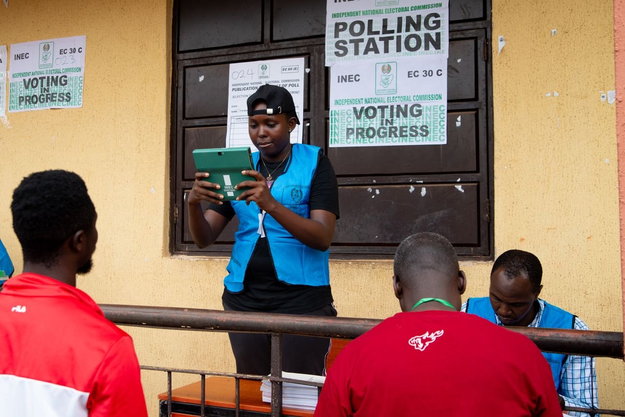 Home Election official in Nigeria assisting voters on election day at a polling station.