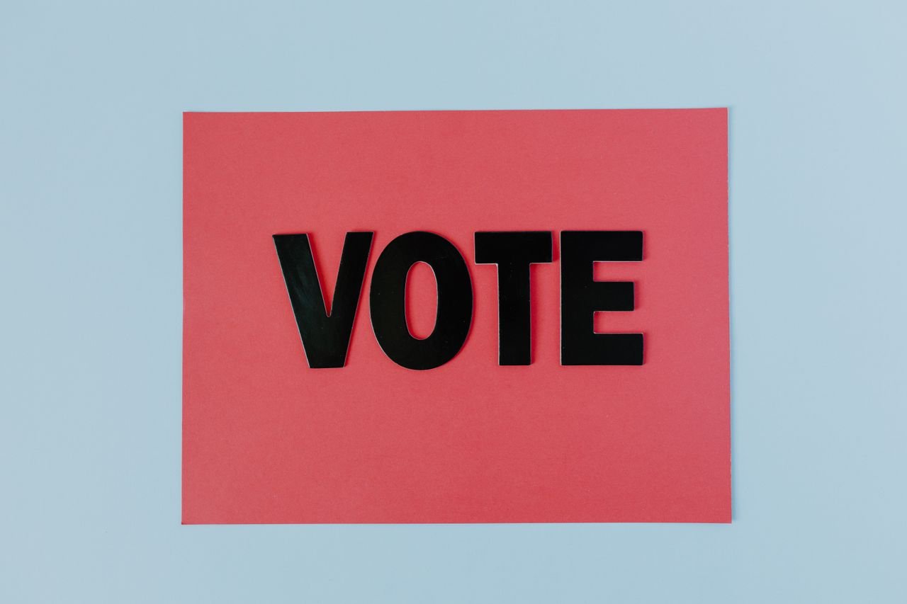 Black letters spelling 'VOTE' on red paper, emphasizing political participation.